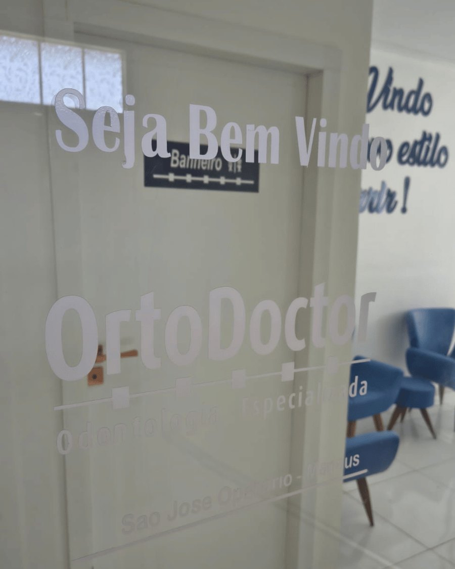 A porta de vidro da OrtoDoctor São José, com o nome da clínica e a recepção ao fundo